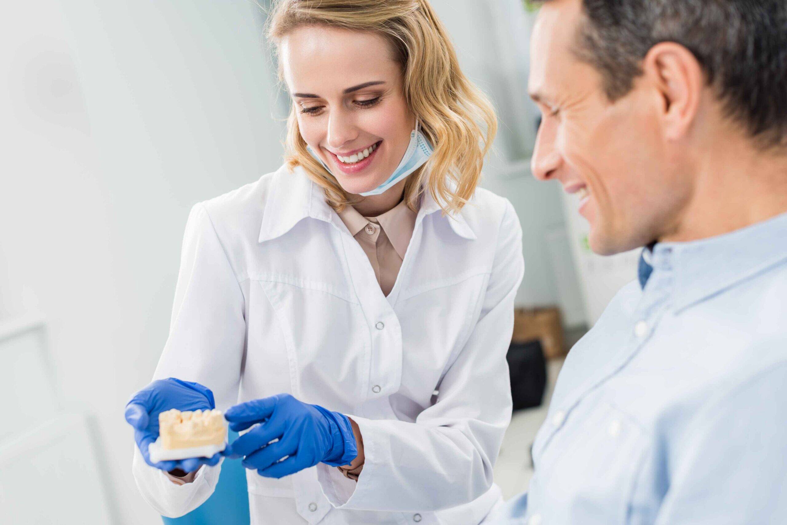 Dentist explaining a dental implant model to a patient.