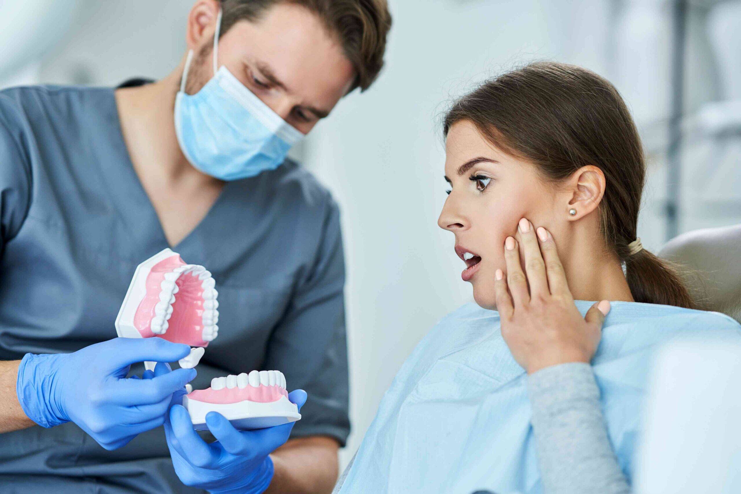 Dentist explaining a dental model to a patient with tooth pain.