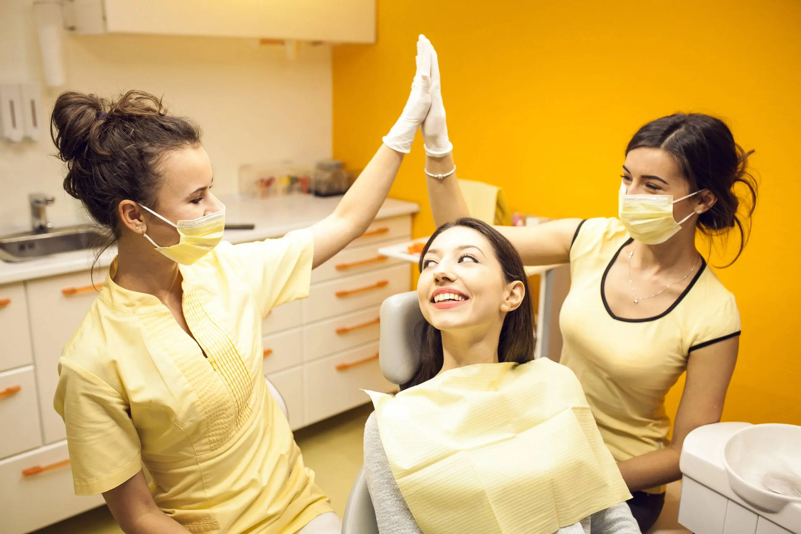 Dental team celebrating with a smiling patient after treatment.