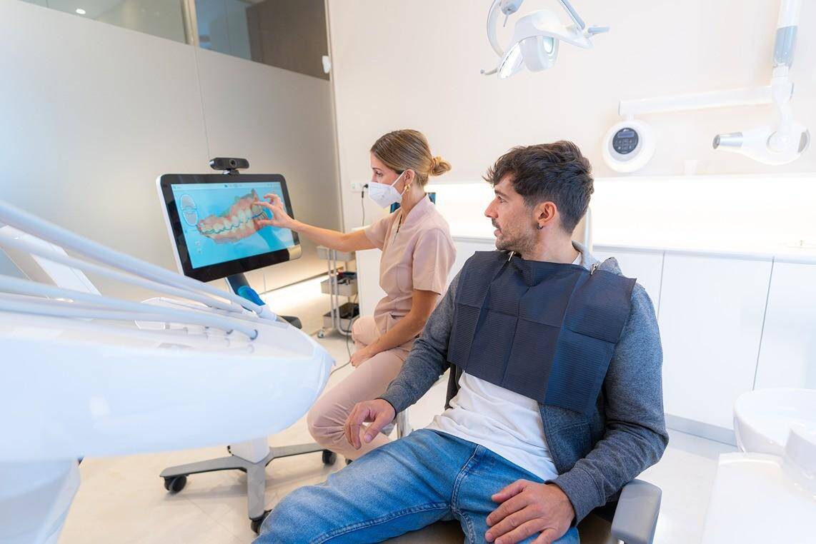 Dentist showing a patient a digital dental scan in a modern clinic.
