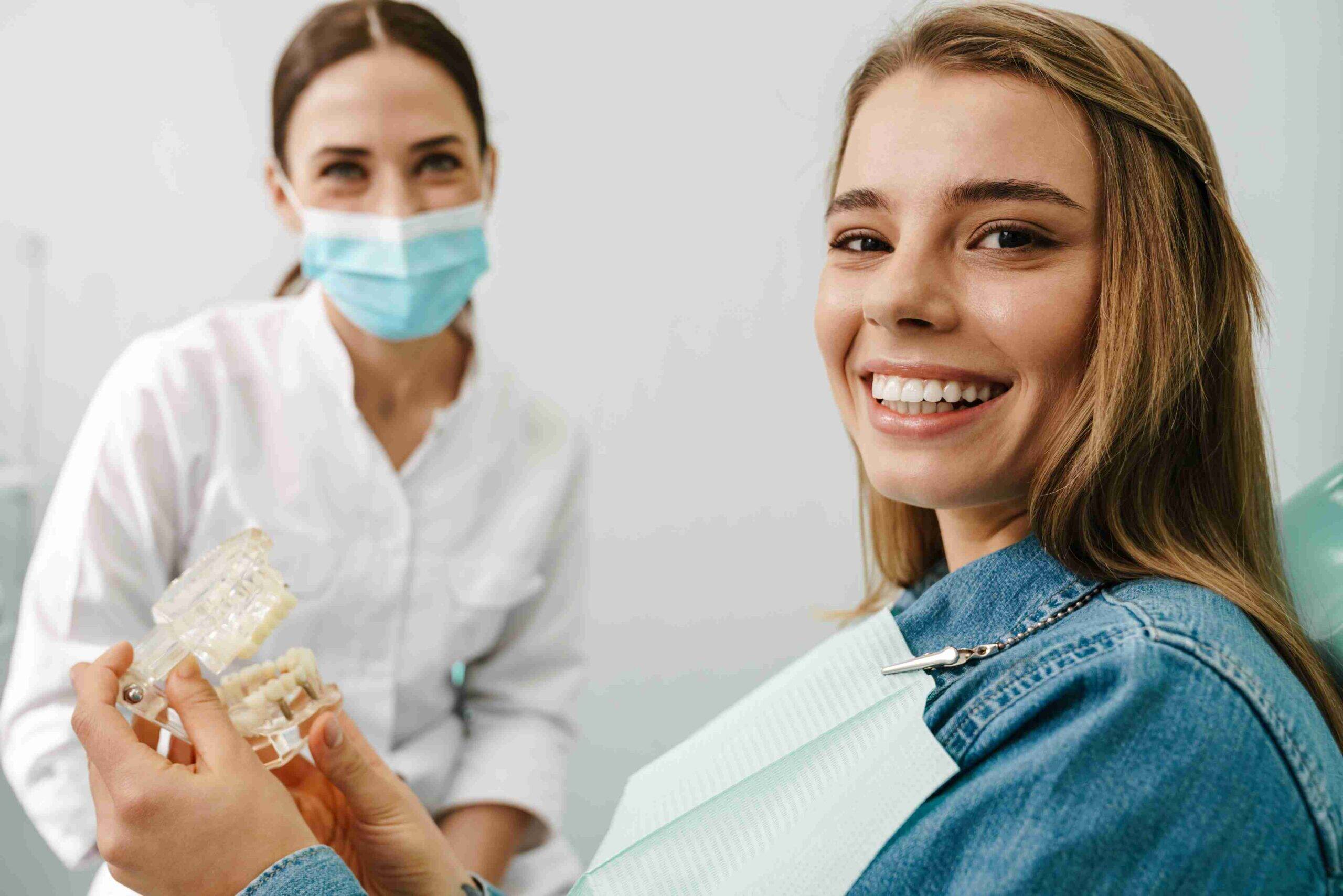 Smiling patient holding clear aligner model.