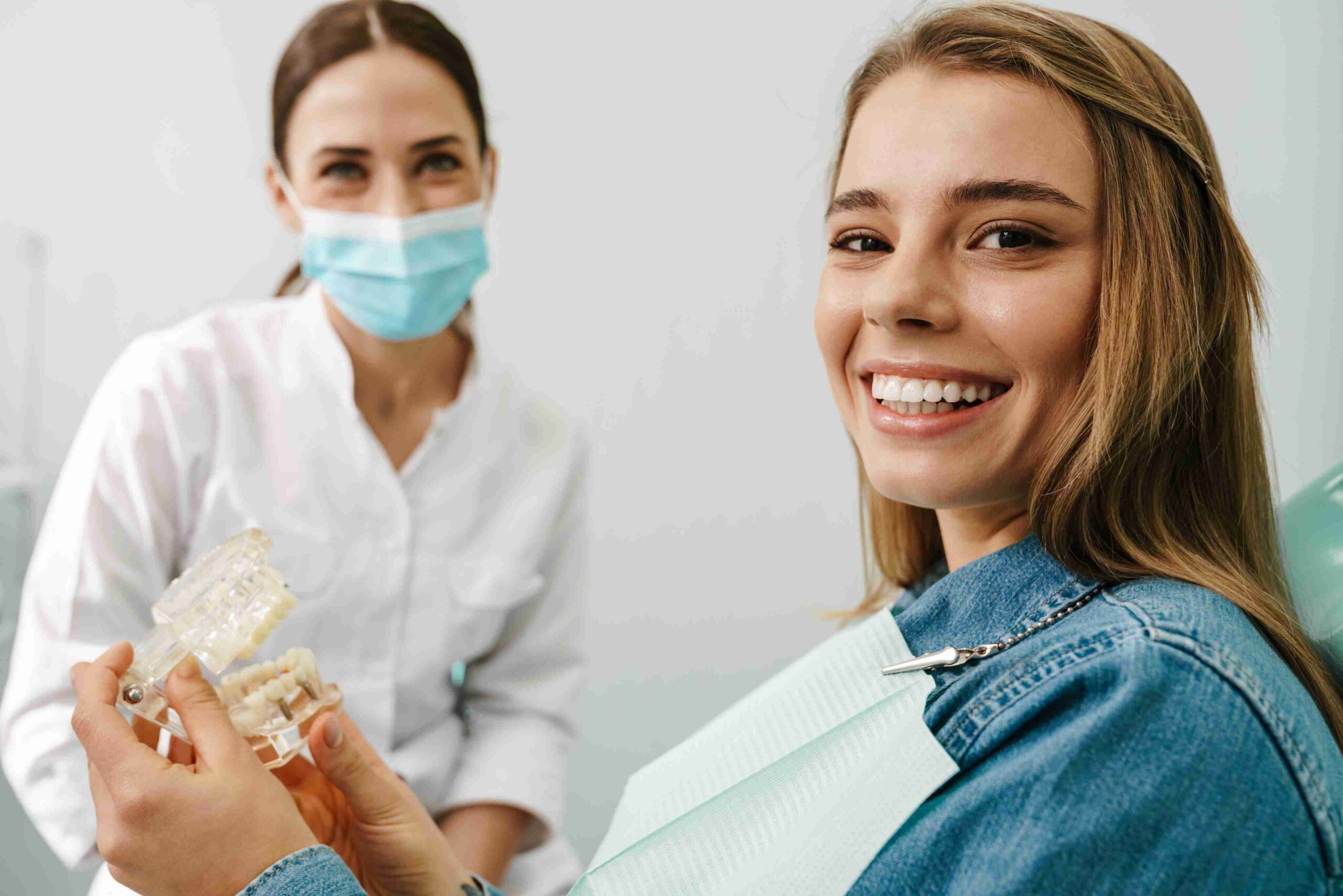Smiling patient holding clear aligner model.